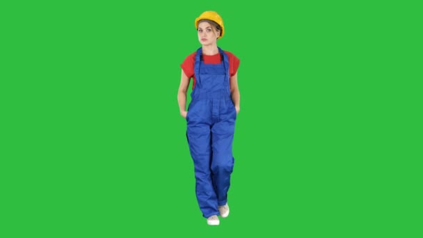 Femme constructeur avec les mains dans les poches marchant et racontant une histoire à la caméra sur un écran vert, Chroma Key . — Video