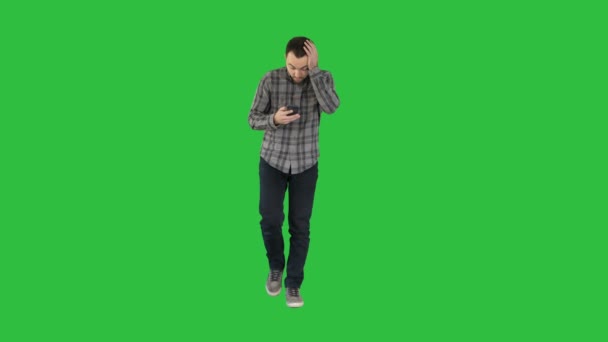 Shoked mladý muž drží telefon a čtení zpráv, při chůzi na zelené obrazovce, Chroma Key. — Stock video