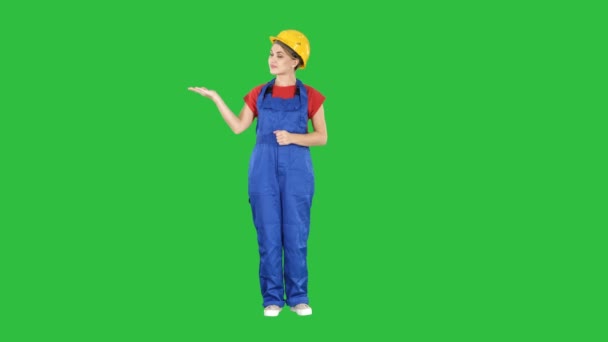 Mature engineer woman presenting a product pointing to side on a Green Screen, Chroma Key. — Stock Video