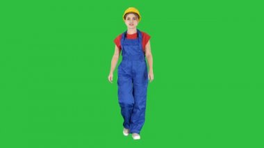 Sarı kask yeşil ekranda Chroma Key yürüyen genç kadın.