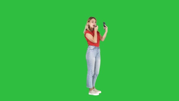 Mujer usando lápiz labial y mirando en su teléfono en una pantalla verde, Chroma Key . — Vídeos de Stock