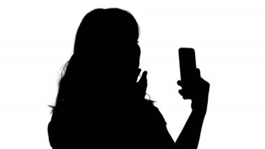 Siluet güzel kadın kendine çeki düzen telefonunu bir ayna gibi kullanarak.