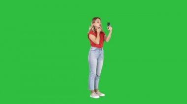 Sarışın kadın bir yeşil ekran, Chroma Key Smartphone'da önünde bakıp.