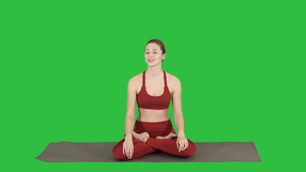 Hermosa mujer sentada en una esterilla de yoga y hablando con alguien en una pantalla verde, Chroma Key . — Vídeos de Stock