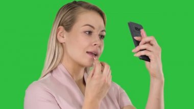 Yakın çekim. Dudaklarını kırmızı ruj ile boyama ve yeşil ekran, Chroma Key telefonla arayan güzel sarışın genç kadın. 4 k çözünürlüklü profesyonel vurulmuş. 005. e.g kullanabilmeniz için