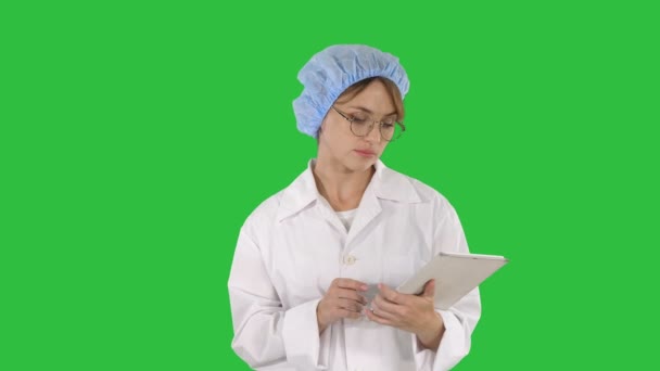 Unga positiva läkare kvinna tar anteckningar på surfplatta och gå på en grön skärm, Chroma Key. — Stockvideo