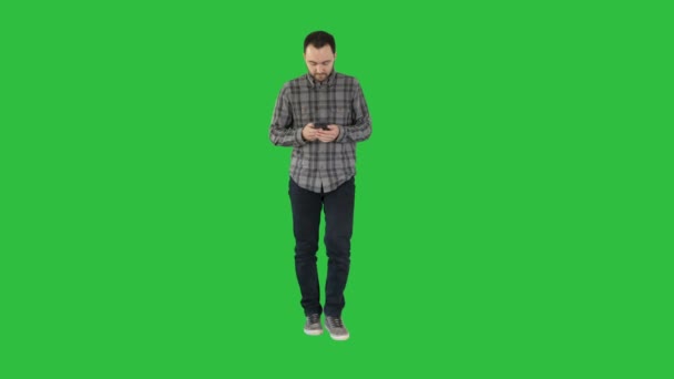 Jonge man lopen en het gebruik van een telefoon, berichten op een groen scherm, Chromakey. — Stockvideo