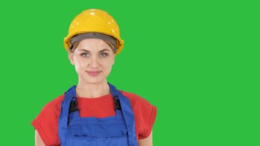 Kalça, elleri ceplerinde Chroma anahtar yeşil ekranda üzerinde duran ve pozlar kat el değiştirme Oluşturucu işçisi kadın gülümsüyor, eller.