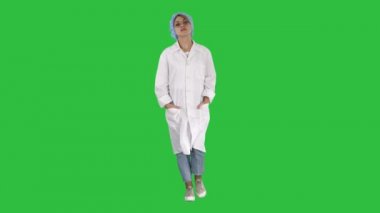 Tek tip bir yeşil ekranda Chroma Key yürüme ciddi beyaz genç bir kadın.