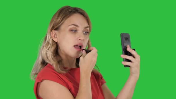 Mujer rubia aplicando lápiz labial mirando en el teléfono en una pantalla verde, Chroma Key . — Vídeos de Stock