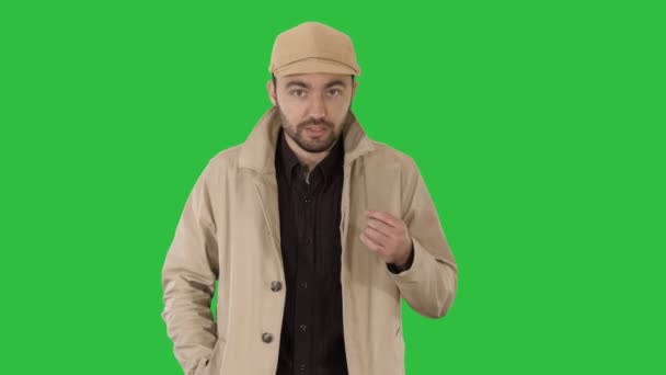 En positiv skäggig man klädd i en trenchcoat promenader och pratar på en grön skärm, Chroma Key. — Stockvideo