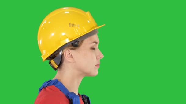 La jeune femme ingénieur avec casque de sécurité jaune marchant et souriant sur un écran vert, Chroma Key . — Video