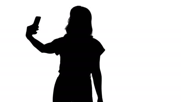 Σιλουέτα Χαριτωμένο κορίτσι κάνει selfie περπάτημα. — Αρχείο Βίντεο