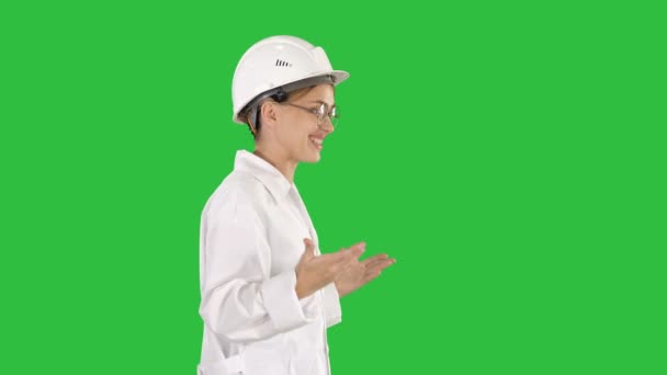 Unga forskare i labbrock och hardhat promenader och säga något på en grön skärm, Chroma Key. — Stockvideo