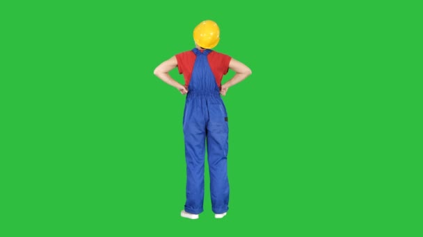 Kvinna ingenjör i byggarbetarhjälm står med händerna på höfterna på en grön skärm, Chroma Key. — Stockvideo