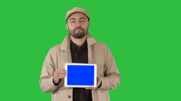 Uomo in trincea che cammina e tiene tablet con mockup schermo blu che presenta qualcosa su uno schermo verde, Chroma Key . — Video Stock