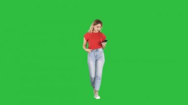 Sarışın kadın manifatura bir yeşil ekranda Chroma Key yürüyüş onun akıllı telefon ile.