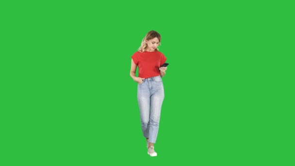 Szőke nő textil ő gyaloglás-ra egy zöld képernyő, Chroma Key okostelefonnal. — Stock videók