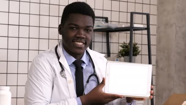 Leende läkare presenterar produkten på en handdator. Vit skärm. — Stockvideo