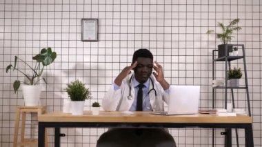 Çünkü çaresiz ve stresli baş ağrısı acı genç Afro-Amerikan Doktor ağrı ve migren. Ellerini kafasına.