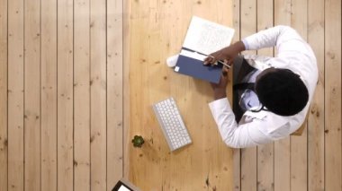 Notlar bu pisliği ile masa başında oturan erkek doktor yazıyor.