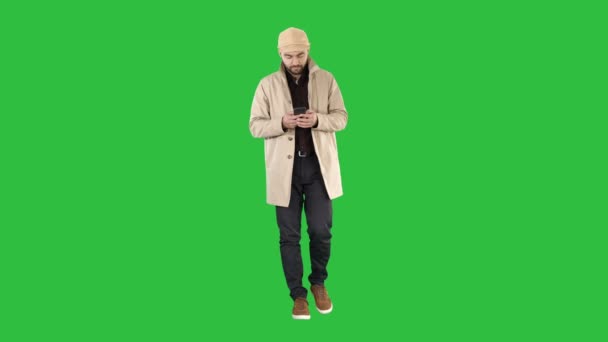 Schöner Mann in Mantel zu Fuß und SMS-Nachricht auf dem Telefon auf einem grünen Bildschirm, Chroma-Schlüssel. — Stockvideo