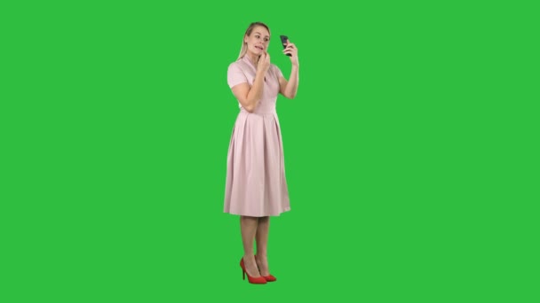 应用口红的妇女看着她的手机在绿色屏幕上, 色度键. — 图库视频影像