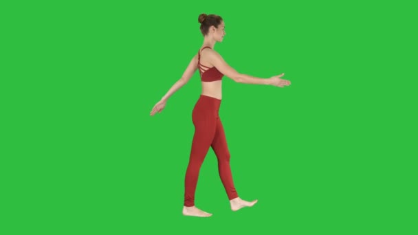De blonde yoga-instructeur wandelen en zwaaien haar handen op een groen scherm, Chromakey. — Stockvideo