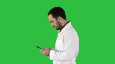 Doktor veya hemşire manifatura Chroma anahtar yeşil ekranda bir cep telefonuyla yürüyüş.