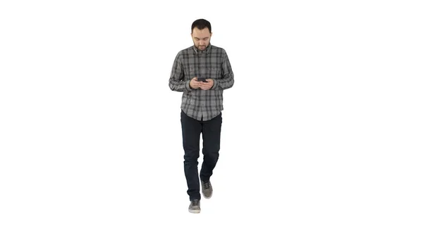 Молодий чоловік ходить і використовує телефон, обмін повідомленнями на білому тлі . — стокове фото