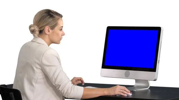 在办公室工作的年轻女子, 坐在办公桌前, 看着显示器, 白色背景。蓝屏模拟显示. — 图库照片