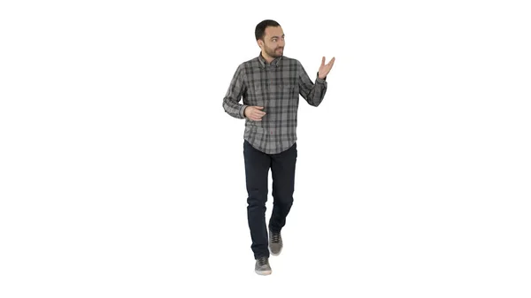 Jovem homem confiante em camisa e jeans caminhando em direção à câmera e apontando para os lados no fundo branco . — Fotografia de Stock