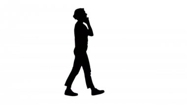 Siluet. Güzel genç kız, yürürken telefonla konuşuyor..