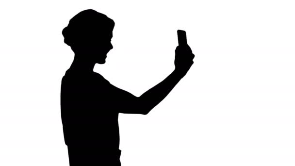 Silhouette vacker ung kvinna promenader och hålla en smartphone upp till ta bilder och selfies. — Stockvideo