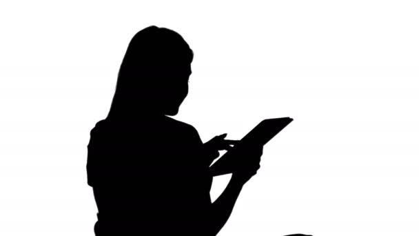 Silhouette Woman sitter och tittar på tablet pc och ler. — Stockvideo