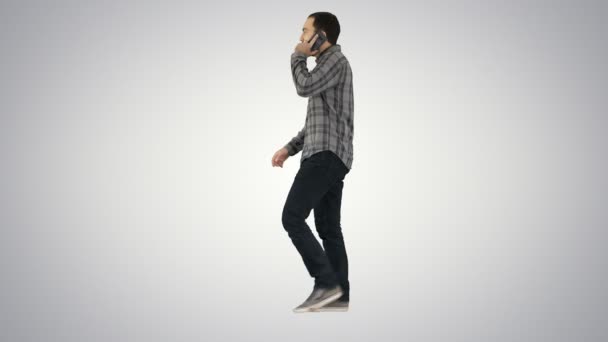 Молодой бородатый мужчина ходит и разговаривает по мобильному телефону на градиентном фоне . — стоковое видео