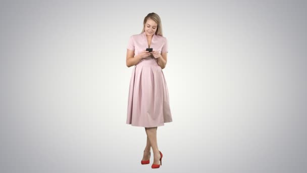 Retrato de uma menina muito sorridente em roupas de verão usando telefone celular, mensagem de texto no fundo gradiente . — Vídeo de Stock