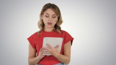 Bir tablet üzerinde gradyan arka planı kameraya konuşurken ciddi bir yüz ile onun elinde tutan kırmızı t-shirt giyen bayan.