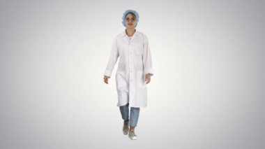 Gülümseyen çocuk doktoru üniforma ceplerinde el ele tutuşuyor ve arka planda yürüyor..