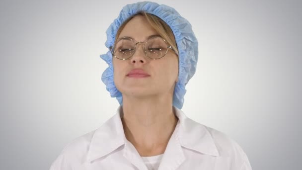 Woman doctor in glasses and hat walking and looking around on gradient background. — Stock Video