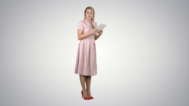 Female young woman in pink standing with tablet and giving speech to camera on gradient background. — Stock Video