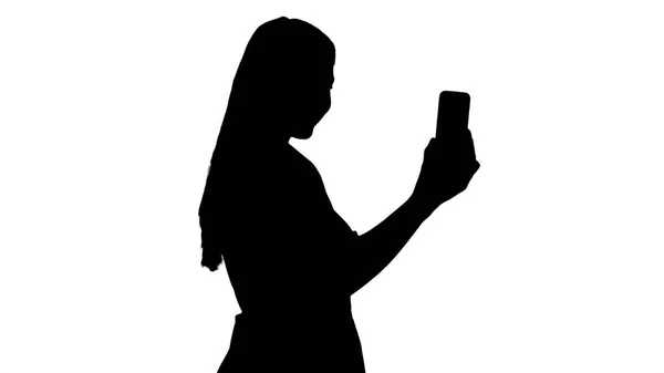 Silhouette weiblich in rosa Kleid macht Videoanruf mit ihrem Smartphone. — Stockfoto