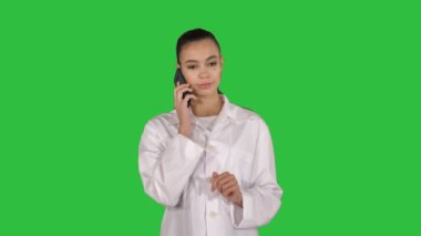 Orta atış. Chroma anahtar yeşil ekran yürürken konuşuyor telefonda gülümseyen kadın doktor. 4 k çözünürlüklü profesyonel vurulmuş. 013. sen-ebilmek kullanma o bir örneğin ticari video, işinizde