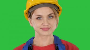 Sarı kask yeşil ekranda Chroma Key yürüyen genç kadın.