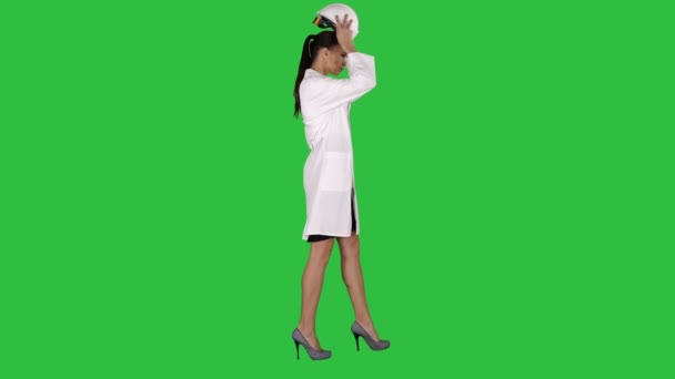Mujer en bata blanca que se pone el sombrero duro mientras camina en una pantalla verde, Chroma Key . — Vídeos de Stock