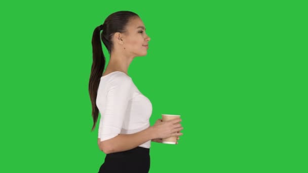 Ontspannen stijlvolle zakenvrouw drinken koffie lopen op een groen scherm, Chromakey. — Stockvideo