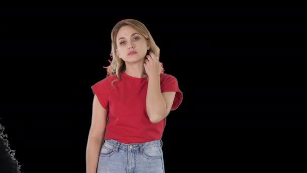 Mujer joven con el pelo rubio en camiseta roja mirando a la cámara sin emociones, Alpha Channel — Vídeos de Stock