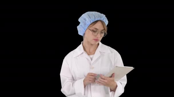 若い正の医師の女性は、タブレットや歩行にメモを取ります,アルファチャンネル — ストック動画