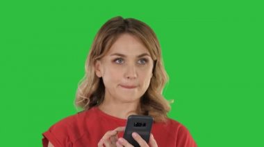 Düşünce güzel sarışın bir yeşil ekranında, Chroma Key telefonunda bir metin gönderme.