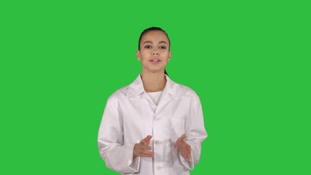 Vrouw arts uit te leggen en te praten met de camera tijdens het wandelen op een groen scherm, Chromakey. — Stockvideo